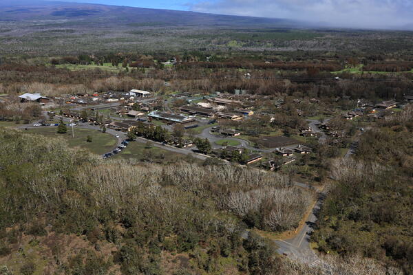 Color photograph of military camp surrounded by forrest and volcano