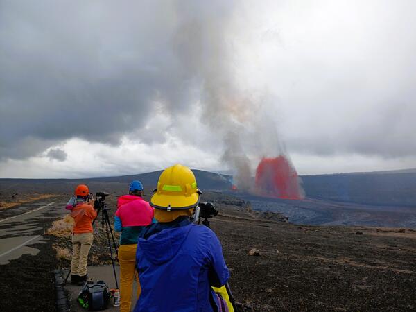 Color photograph of scientists observing volcanic eruption