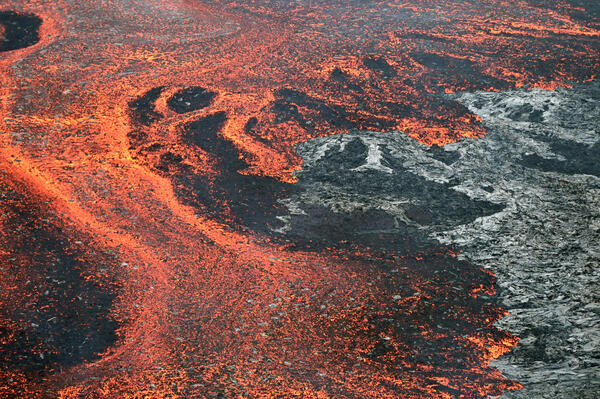 Color photograph of active lava flow on top of inactive lava flow