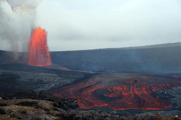 Color photograph of lava fountain and lava flow with crater