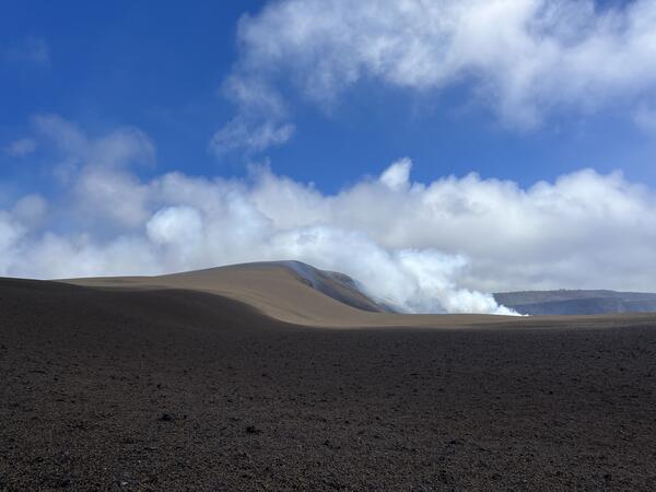 Color photograph of volcanic landscape with volcanic plume and clouds