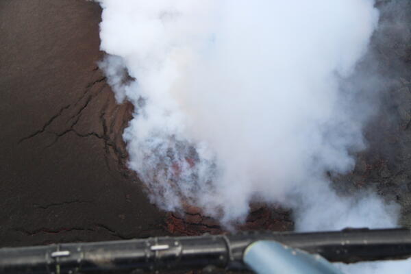 Color photograph of volcanic vent degassing with lava below