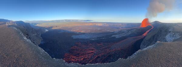 Color panoramic photo of volcanic crater with lava fountain and flows