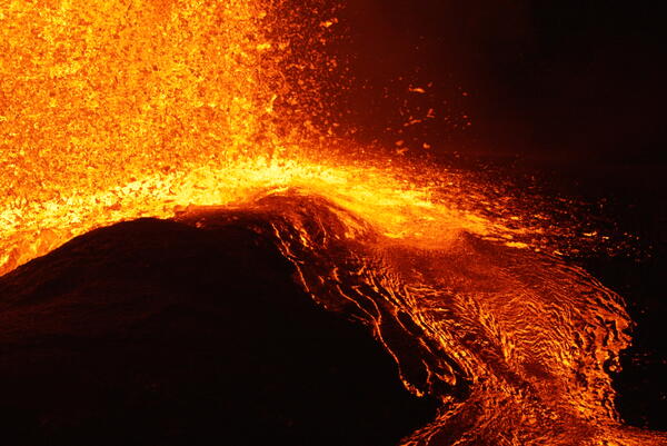 Color photograph of molten volcanic spatter landing in a lava flow