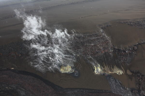 Color photograph of steaming volcanic vents on crater wall