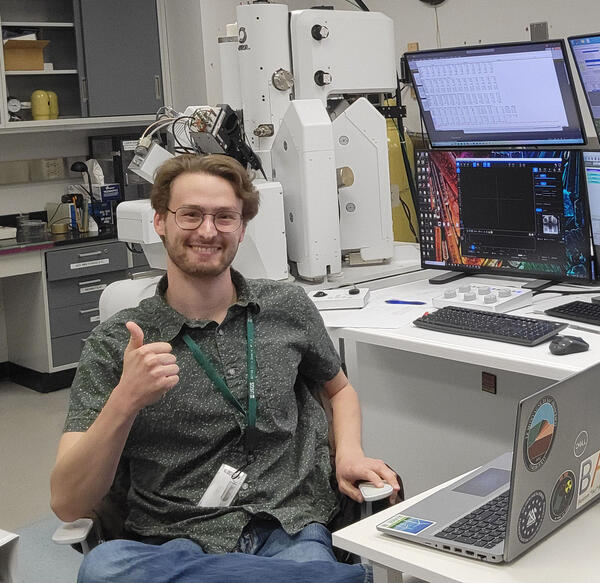 Nicholas E Powell gives a thumbs up while proudly showing off lab equipment