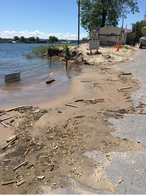 An image showing a lake and beach with recent signs of flooding with trash and debris on the shore. 