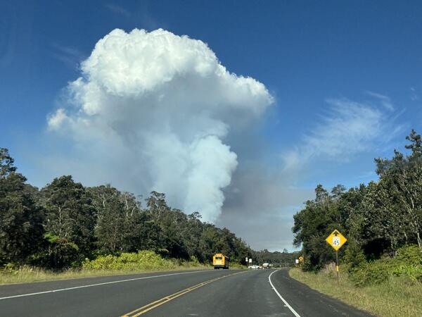 Color photograph of volcanic plume rising above road
