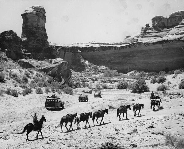 Historic photograph of a group of cars and people on horses in 1965 in Canyonlands National Park