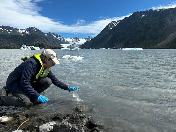 Scientist takes a water sample from a glacial lake in Alaska