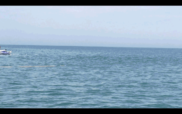 A seismic instrument on pontoon floats is deployed from the beach to the water. 