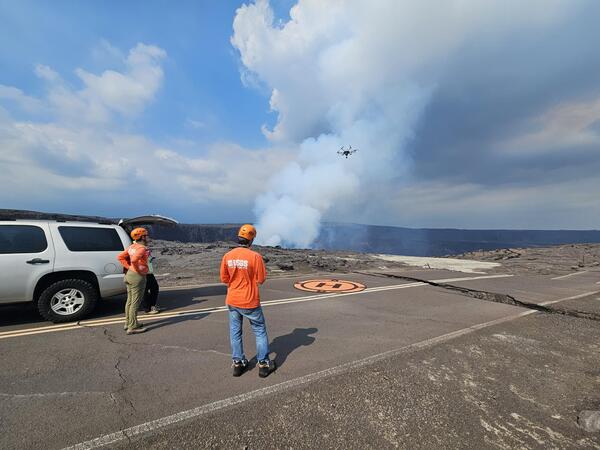 Color photograph of scientists near car operating UAS