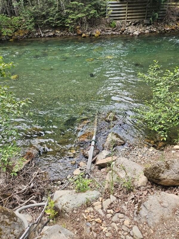A pipe lays in a blue-green river.