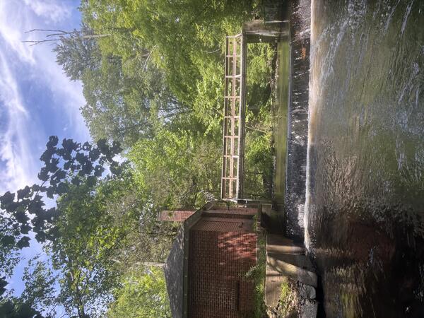 Looking upstream at a footbridge over a river next to a brock house