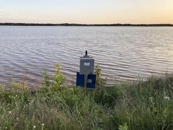 USGS streamgage on grassy lake shoreline at sunset
