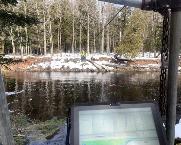 Hydrologic technician takes acoustic Doppler current profiler streamflow measurement from the center of a river via cableway
