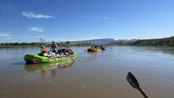 Rafts floating down middle of river.