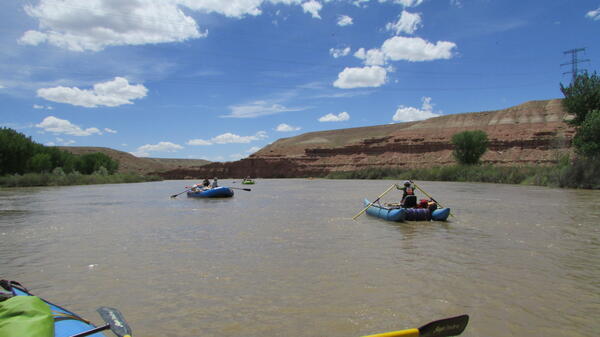 Rafts floating by red bluffs.