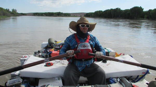 Guy in hat rowing raft.