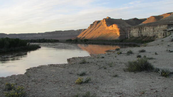 Light hits bluff over river at sunrise.