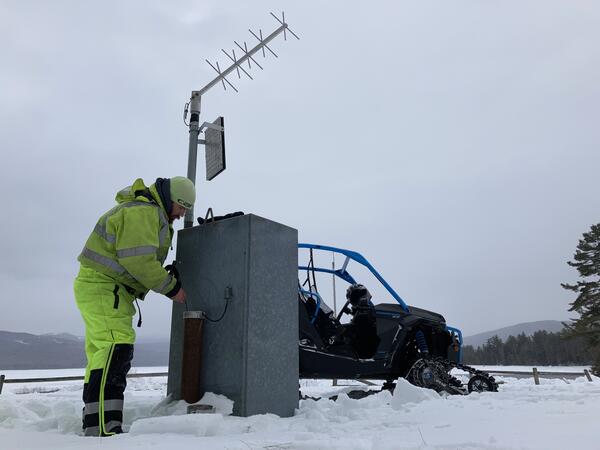 Person looking a streamgage surrounded by snow