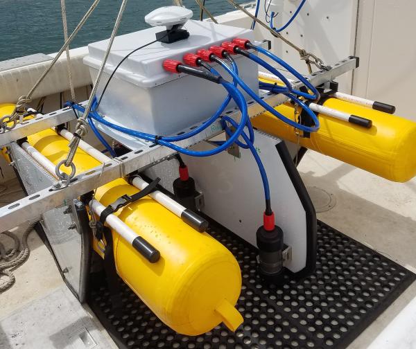 Scientific equipment mounted on two yellow pontoons sitting on the deck of a research vessel