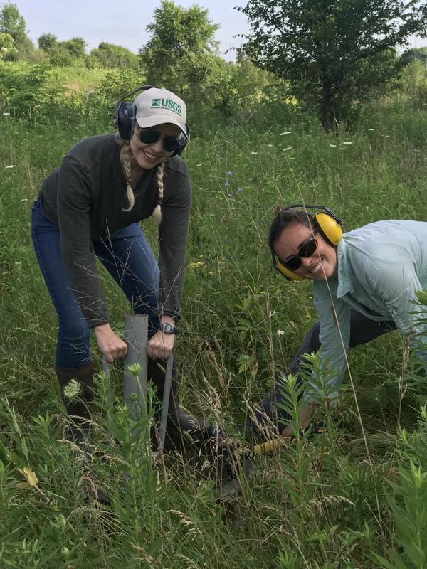 Photo: USGS scientists install a double ring infiltrometer in a grassy field.