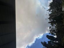 A towering volcanic plume rising above Kīlauea beneath a blue sky