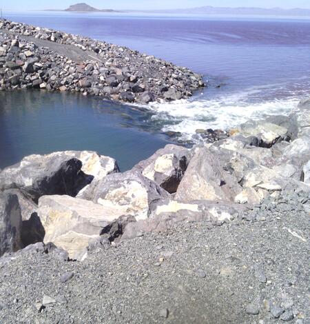 A rocky causeway divides the waters of the Great Salt Lake, with distinct color variations visible between the north and sout