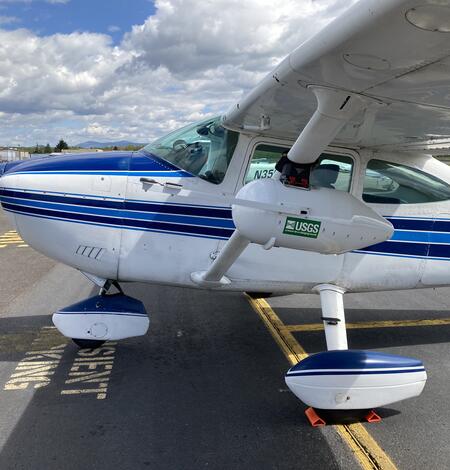 a small white aircraft with a blue, white, and black stripes running down the middle and plane nose.