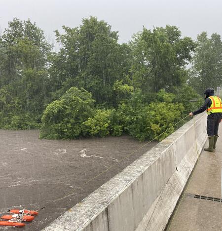 USGS water data expert Garret Welsh measures water flow in the pouring rain at the Straight River near Faribault, Minnesota. 