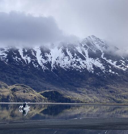 boat sits on lake with large mountains in the background
