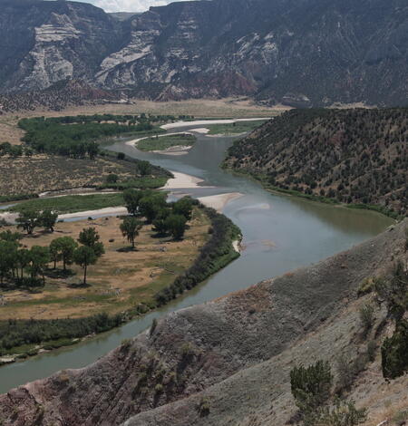 panoramic, aerial shot of a river bending through shrublands and mountains