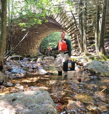 Hydrologic Technician stands in Kebo Brook in Acadia National Park