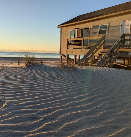 Sky, ocean, sandy beach, and house on beach