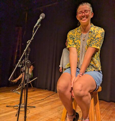 person sitting on stool next to microphone smiling