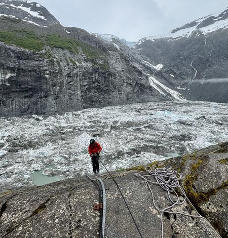 Person in a red jacket standing near a basin covered in ice.
