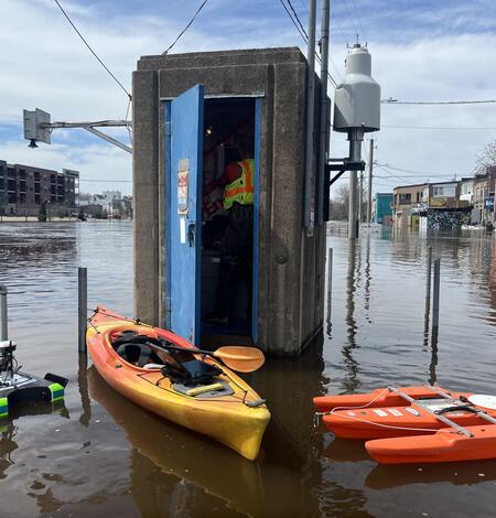 Hydrologic technician inside gage house with kayak and two ADCPs floating outside