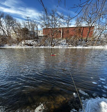acoustic Doppler current profiler floats in middle of river attached to cable across on a winter day