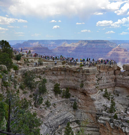 a crowd of people in the distance stand on top of a large viewing platform in the grand canyon