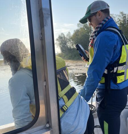 Two scientists measure water quality from a boat