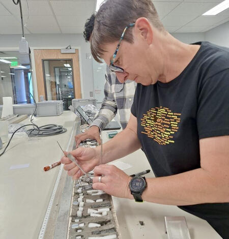 Scientist in a lab collecting samples from an open sediment core