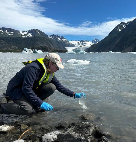 Scientist takes a water sample from a glacial lake in Alaska