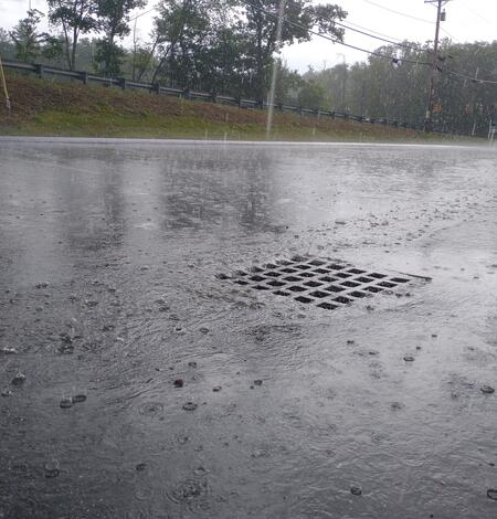 A stormdrain in a parking lot during a rainstorm.