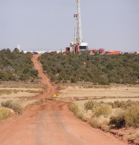 Drill rig in the distance off a dirt road in a semi-aid system