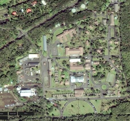 Satellite image of buildings and roads surrounded by grass and vegetation