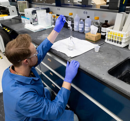 scientist using pipette to fill a flask