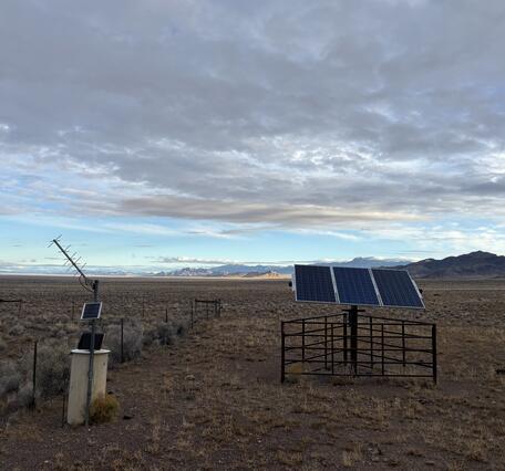 Groundwater monitoring station in desert at dusk with silhouetted mountains in the background.