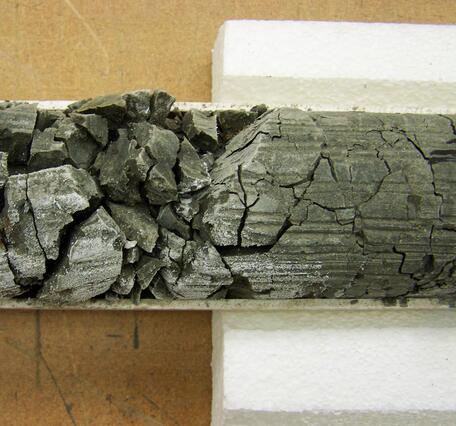 Dark, crumbly rock in a core tube