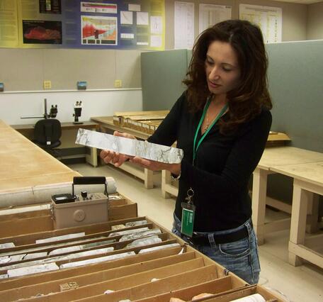 Woman holds and examines a piece of rock core